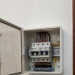 Tủ điện nhánh nhỏ gắn trên tường trong phòng, nắp mở cho thấy vài aptomat