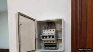 Tủ điện nhánh nhỏ gắn trên tường trong phòng, nắp mở cho thấy vài aptomat